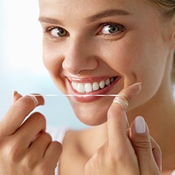 Dental patient using dental floss with white smile